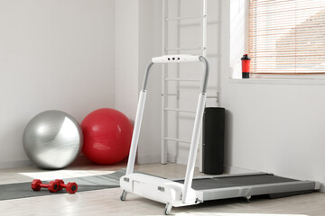 Interior of light gym with treadmill and sports equipment