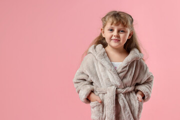 Cute girl in bathrobe on pink background. Space for text