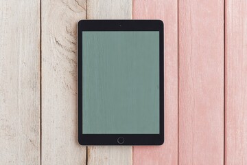 Tablet device rests on a split wooden surface of light wood and pink.