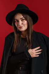 Fototapeta premium Beautiful young woman in stylish clothes posing on red background