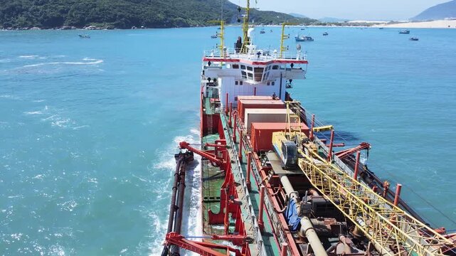 Aerial view of a dredging vessel operating offshore, showing the ship during maritime operation, suction dredger on the coast widening the sand strip beach.