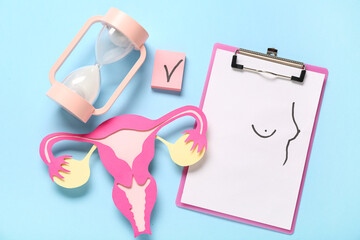 Clipboard with drawn breasts, hourglass, paper uterus and check mark on blue background. Gynecology concept