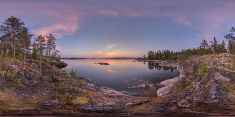 View of serene waters mirroring the pastel sky, framed by rugged rocks and verdant trees under a soft, ethereal light, Sortavala, Russia.
