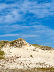 Large white sand dune formations with wild grasses under blue sky in Leba Poland Baltic coastal area. High quality photograph