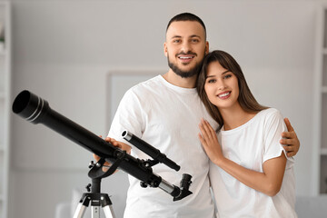 Young couple with telescope hugging at home
