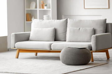 Naklejka premium Laptop on grey pouf in living room interior