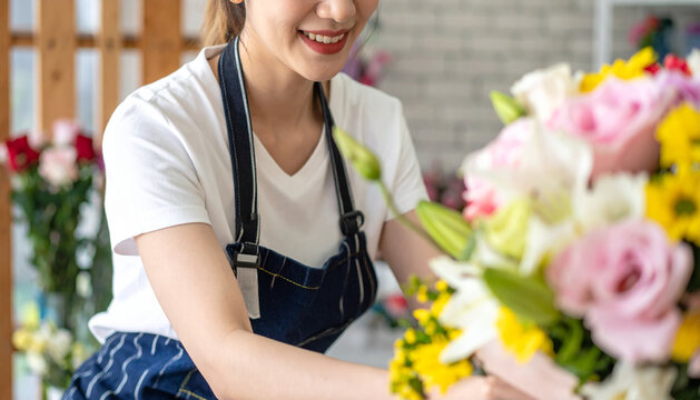 Smiling lovely young woman florist arranging plants in flower shop
