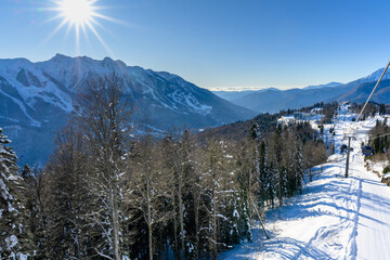 Snowy mountain slopes, a view from above of ski trails and cable cars.