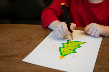 A girl draws a Christmas tree with a marker. High quality photo