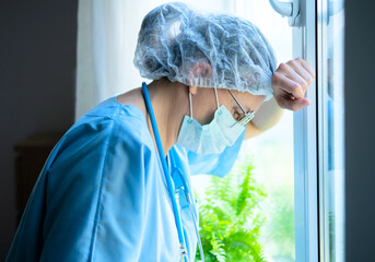 An exhausted female medical professional in uniform thinks deeply about patient care plan, showing the difficult work of hospital staff.