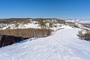 Ski trail limited by a wooden fence against the backdrop of a picturesque landscape of the Ural Mountains.