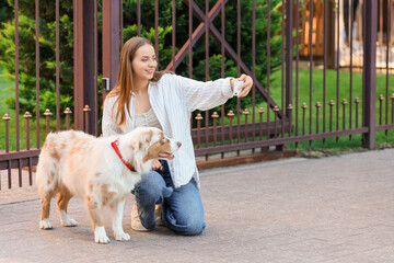 Young woman with Australian Shepherd dog taking selfie on street