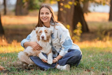 Young woman with cute Australian Shepherd dog sitting in park