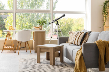 Interior of living room with telescope, sofa and workplace