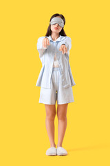 Female sleepwalker in pajamas on yellow background