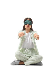 Female sleepwalker in pajamas sitting on white background