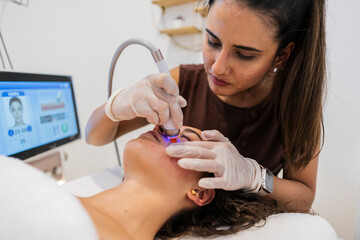 Esthetician performing advanced facial skin treatment using machine