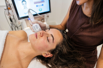 Woman receiving facial treatment with modern device