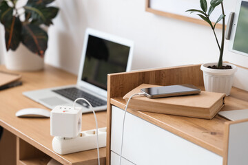 Charging mobile phone with book on shelf in office
