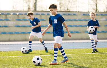 Obraz premium Boys In Football Training With Balls. Children Playing Soccer – Youth Football Training and Match on an Outdoor Field. Kids Soccer Practice, Sports Education, and Team Development