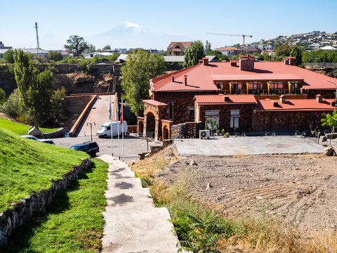 Yerevan, Armenia - September 24, 2025: path to renovated old Red Bridge from red tuff stone accross Hrazdan river, hotel building and view of Ararat mount in Yerevan city on sunny day