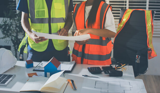 Closeup of team of industrial engineers meeting analyze machinery blueprints consult project on table in manufacturing factory. Working in manufacturing plant or production plant.