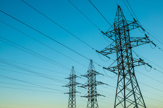Three tall power lines are in the sky, with a blue sky in the background
