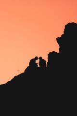 A couple is silhouetted against a backdrop of a sunset