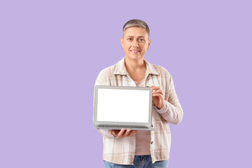 Young woman with short hair and blank laptop on lilac background