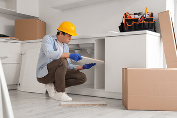 Male worker assembling counter with shelf in kitchen