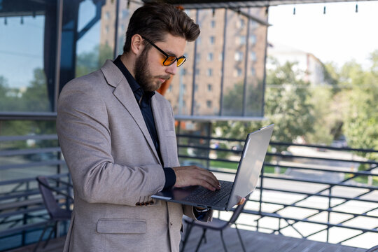 A man is working on his laptop on a balcony