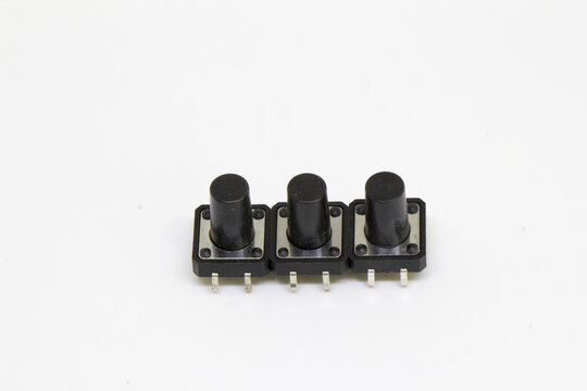 Top-down view of three long-stem tactile pushbutton switches aligned side-by-side, isolated on white
