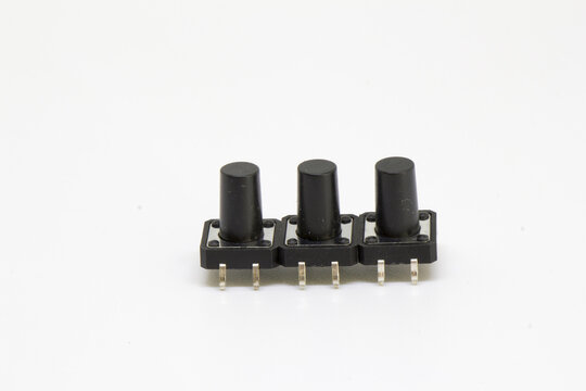 Side/angled view of three long-stem tactile pushbutton switches showing four-pin leads for PCB mounting, isolated on white