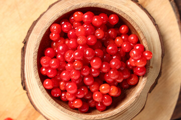 Bowl with fresh viburnum berries on wooden board, closeup