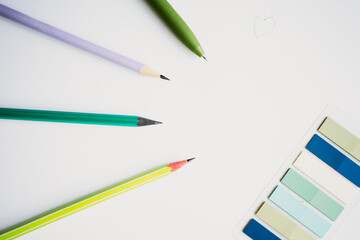Minimalist flat lay of a blank white page, surrounded by colorful pencils, a pen, and pastel sticky notes, representing creativity, planning, and starting new projects