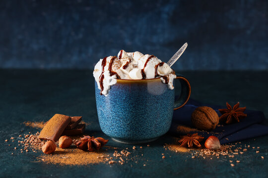 Cup of hot cocoa drink with whipped cream and marshmallows on dark background