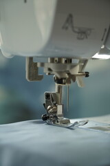 Macro photograph of a sewing machine needle in focus. Perfect for illustrating themes of fashion design, craftsmanship, handmade work, or textile production.