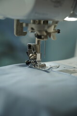 Macro photograph of a sewing machine needle in focus. Perfect for illustrating themes of fashion design, craftsmanship, handmade work, or textile production.