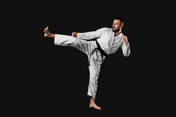 Young man practicing karate on dark background © Pixel-Shot