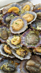Close-up of grilled limpets with garlic and herbs served in their colorful shells