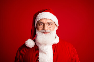 Santa in a classic red suit with white beard and glasses smiling warmly against a bold red background for Christmas holiday themed stock imagery