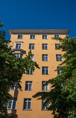 Tall yellow residential building against clear blue sky.