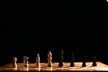 Wide low-key panorama with a thin baseline of pieces across the board; expansive dark space and warm highlights evoke silence before the move.