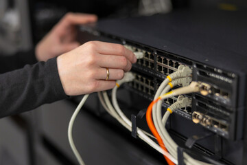 Female IT technician in a datacenter connecting and configuring network switches with cables