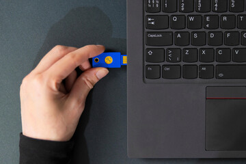 IT security technician using a USB flash drive beside a laptop in a tech office
