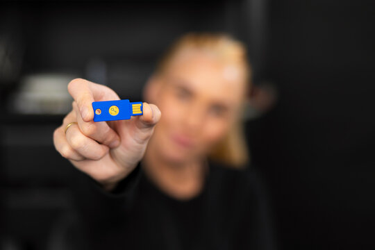 Caucasian woman IT security technician in a tech office holding a blue USB flash drive for data security