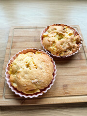 Homemade apple cakes in silicone molds on wooden board. Pastry preparation, sweet baking, and simple dessert recipe at home.