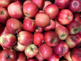 Pile of fresh red apples with smooth skin and natural color variations, creating a vibrant and healthy fruit background.