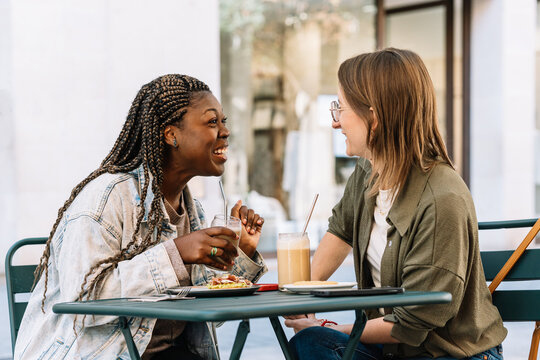 Diverse women friends sharing laughing conversation at cafe