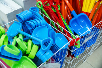 A wide assortment of vibrant plastic snow shovels for children neatly displayed in a store. The...